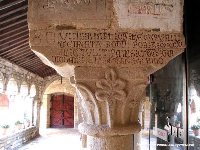 CAPITEL, CON ZAPATA EPIGRAFIADA. AL FONDO, ACCESO EXTERIOR AL CLAUSTRO